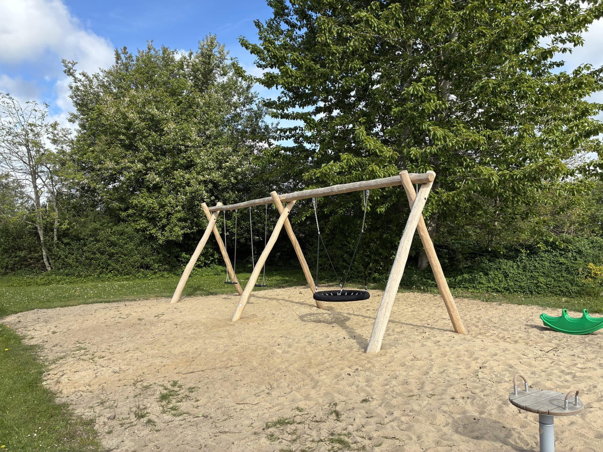 Træ-sving på sandunderlag med træer i baggrunden